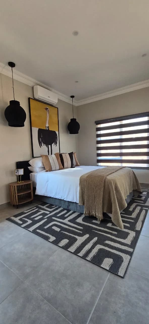 Guest bedroom with patterned rug and striped blinds, Ingele Game Lodge