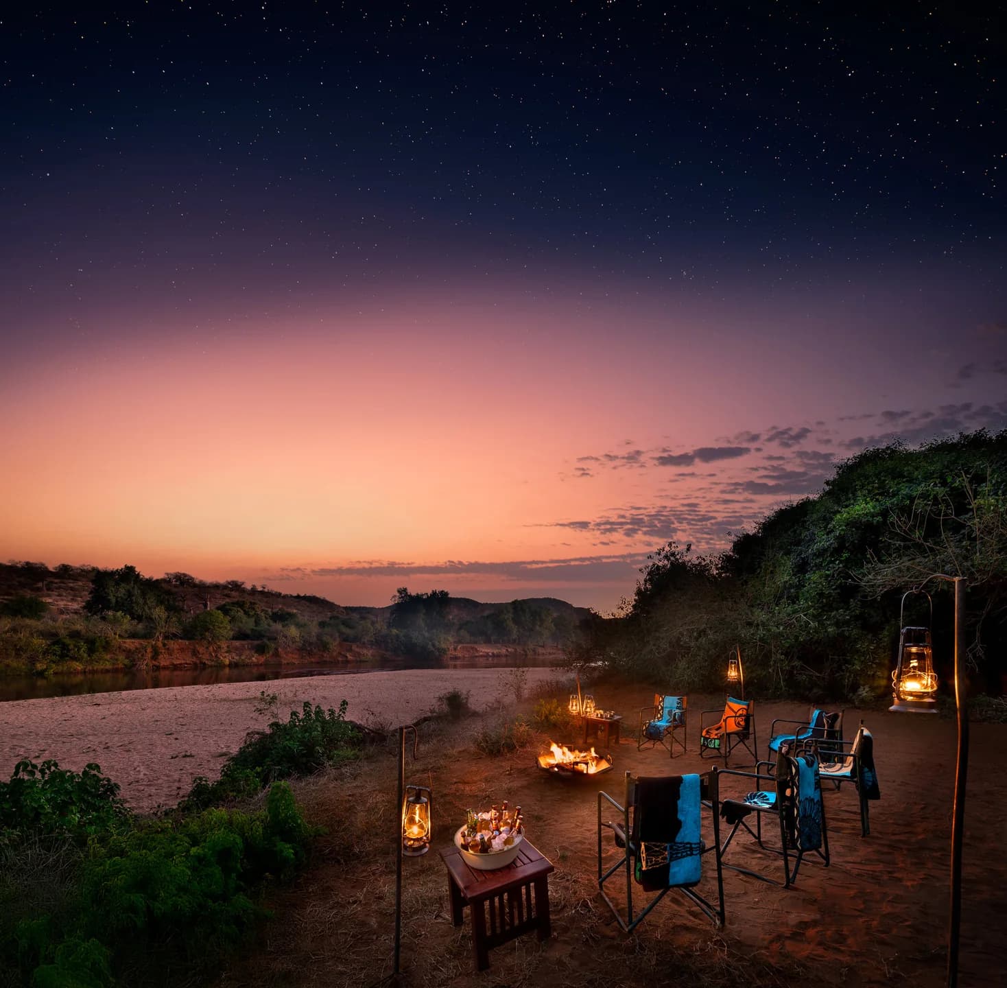 Lanterns and riverside camp seating beneath a twilight sky, Hutwini Walking Camp