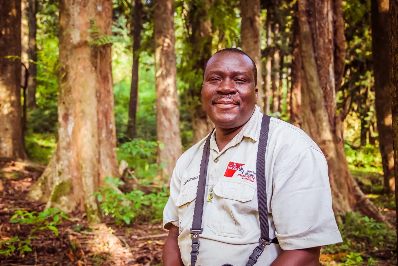 Bird guide with binoculars standing in a forest, Samson Mulaudzi birding