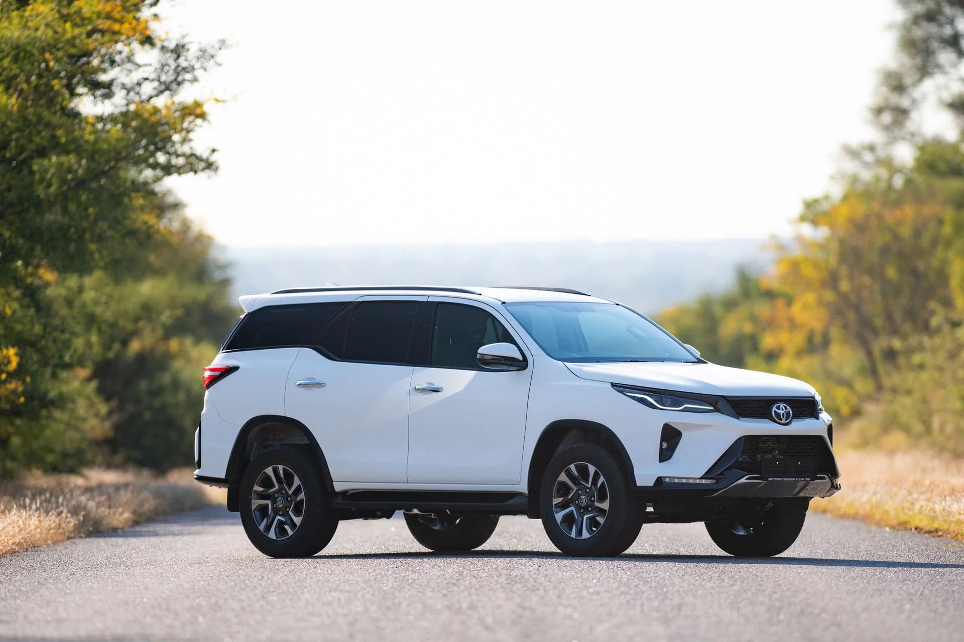White SUV parked on a quiet paved road, Sable Tours transfers and touring