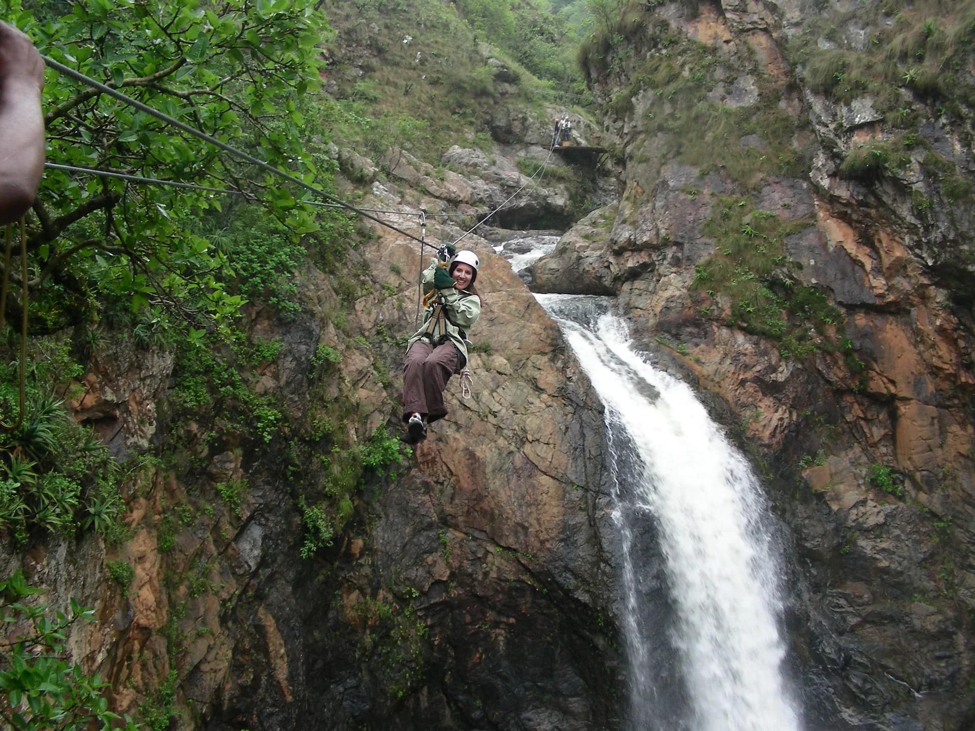 A cable-slide rider crossing a steep gorge above a waterfall, Magoebaskloof Canopy Tour