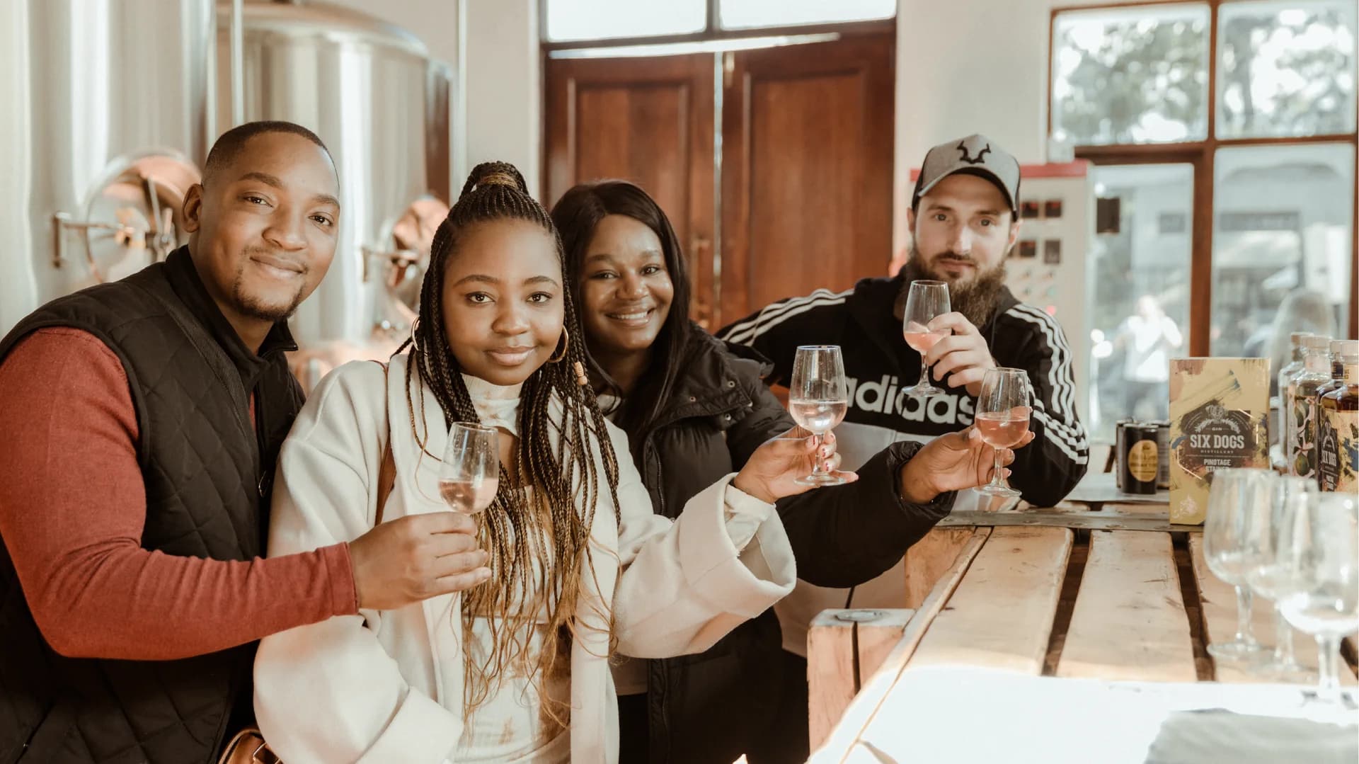 Friends raising glasses at a wooden brewery table, Zwakala Brewery