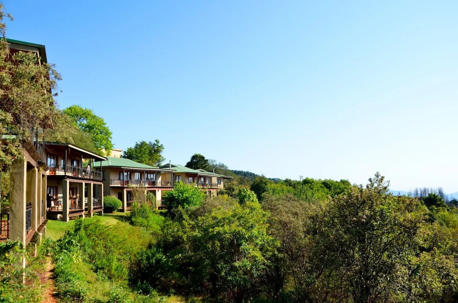 Long balcony-fronted hotel building on a wooded hillside, Magoebaskloof Hotel