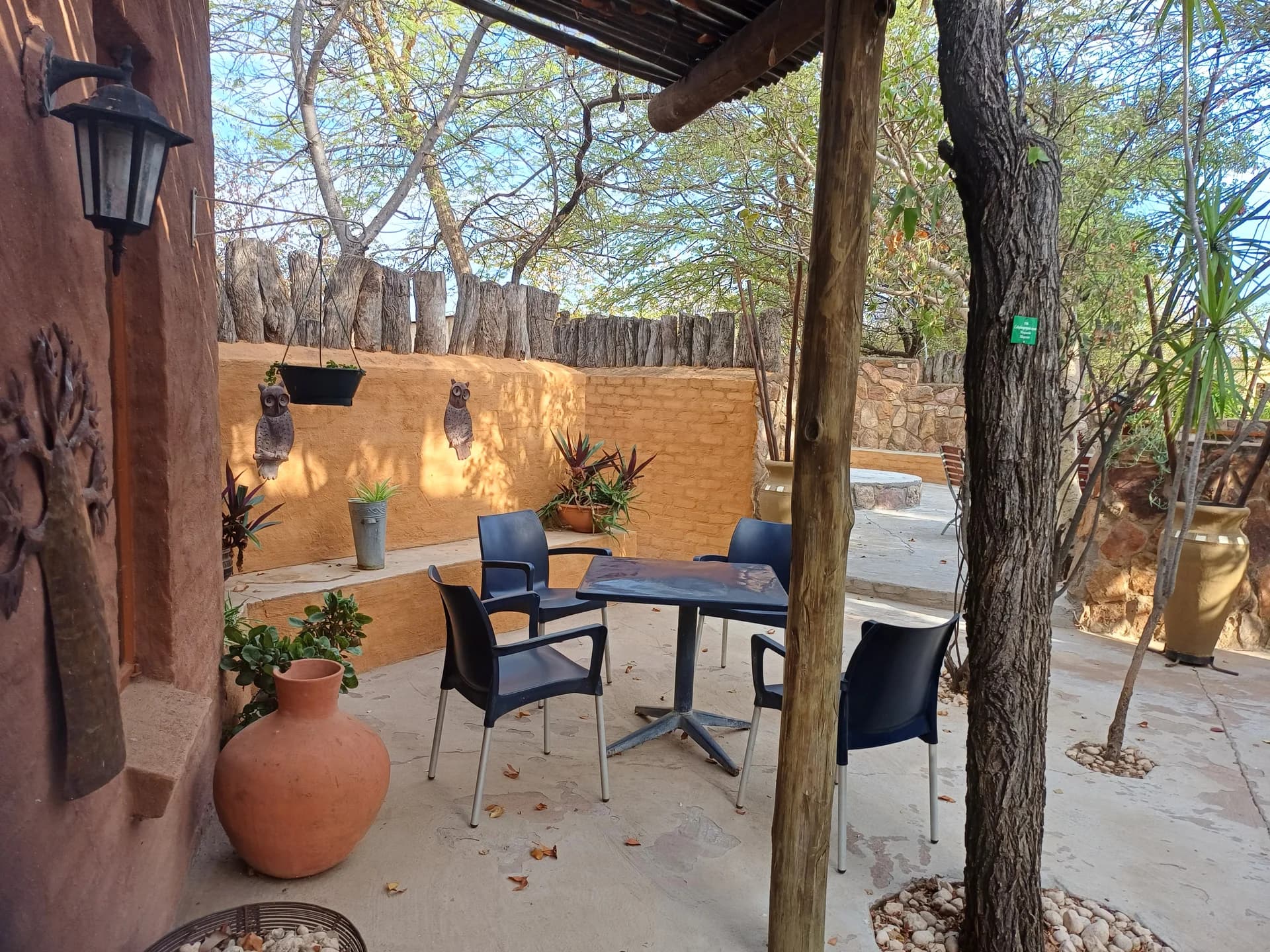 Shaded lodge veranda with timber posts, seating and terracotta pots, Corea Game Lodge