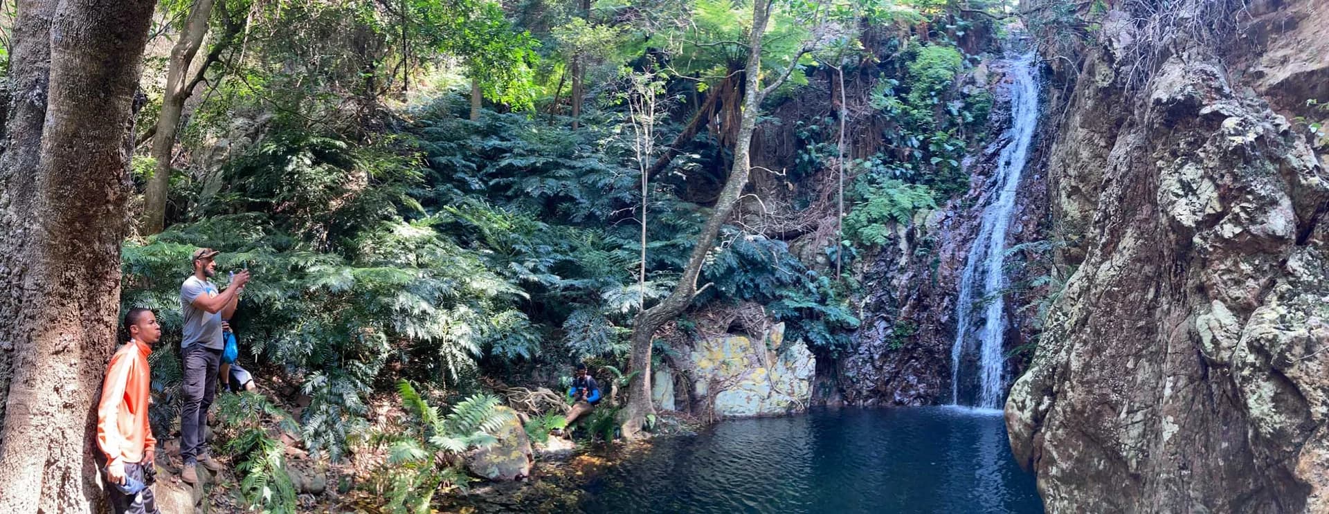 Two walkers beside a forest waterfall and rock pool, Soutpansberg and Venda